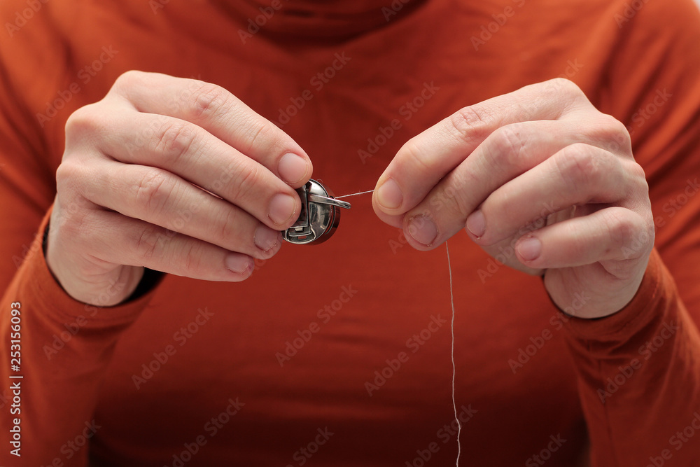 the seamstress holds the bobbin's shuttle with his hands and pulls the thread. sewing process the seamstress holds the bobbin's shuttle with his hands and pulls the thread. sewing process