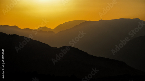 Silhouettes of mountains against the background of the sun. Ru us al Jibal. Al Hajar Moutains. Musandam. Oman