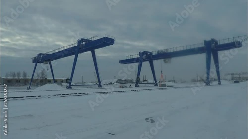 Large gantry cranes in the idustrial zone during working process, time lapse. Cargo cranes near storehouses in the winter evening. photo