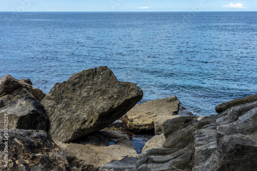 Italy,Cinque Terre,Riomaggiore, a person sitting on a rock near the ocean