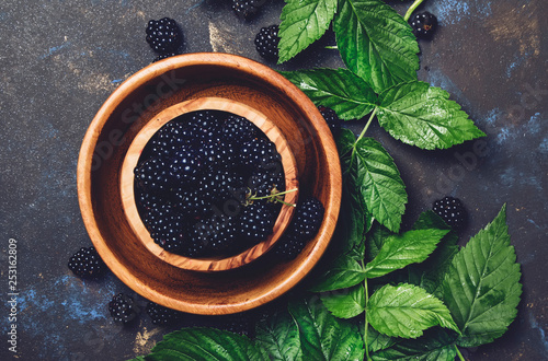 Fresh blackberries with leaves in wooden bowl, copy space, top view