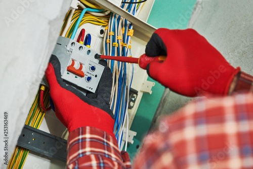 Electrician works with switchbox photo