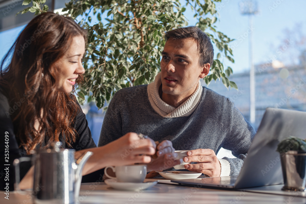 Young man and woman working in front of the laptop and drinking tea. Young man and woman working in front of the laptop and drinking tea.