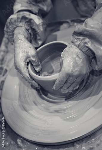 Hands of young girl in process of making crockery on pottery wheel