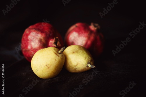 pomegranat and pear on black background