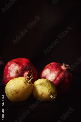 pomegranat and pear on black background
