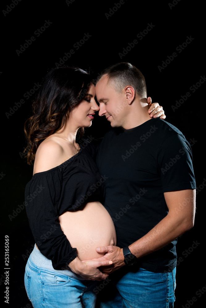 Handsome pregnant couple woman and man an posing on dark black background.  Family love and expectation of the baby Stock Photo | Adobe Stock