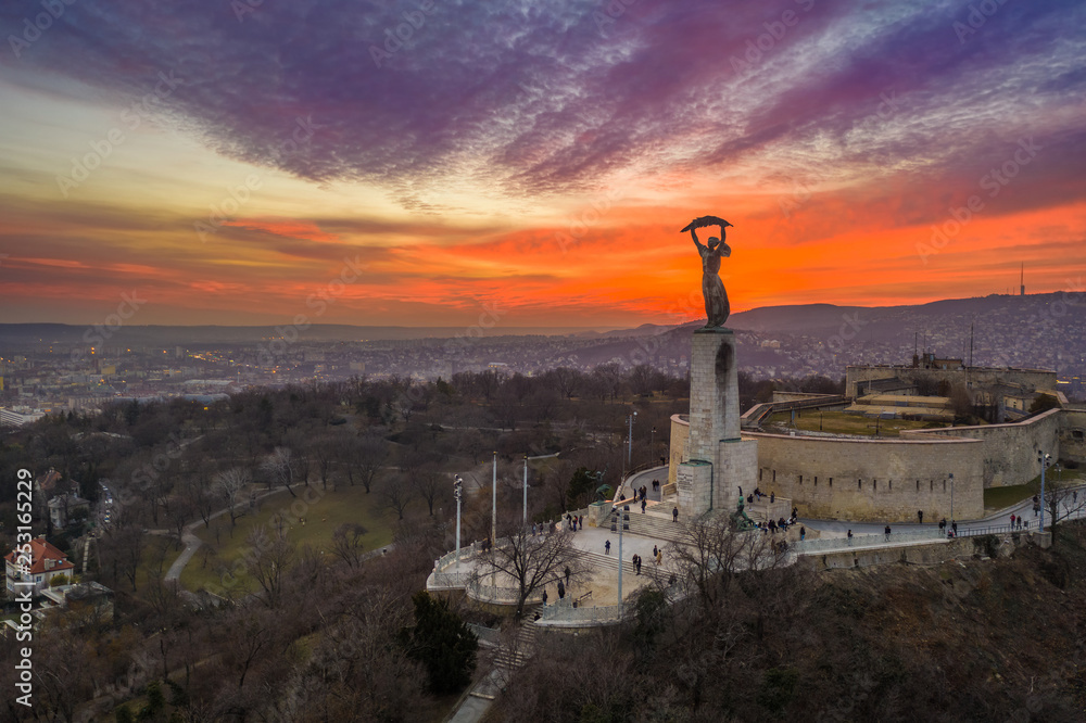 Budapest, Hungary - Aerial view of the Hungarian Statue of Liberty with Buda Hills and amazing colorful sunset behind at winter time
