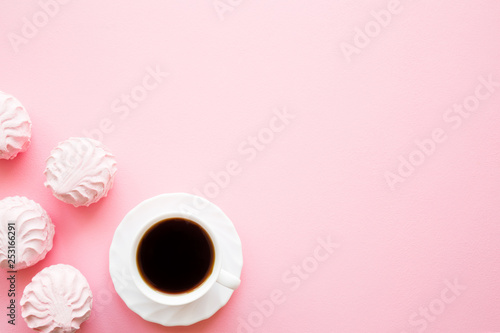 White cup of black coffee with fluffy, airy zephyrs. Mockup for different ideas. Empty place for positive, sentimental text, lovely quote or sayings on pastel pink table. Flat lay.