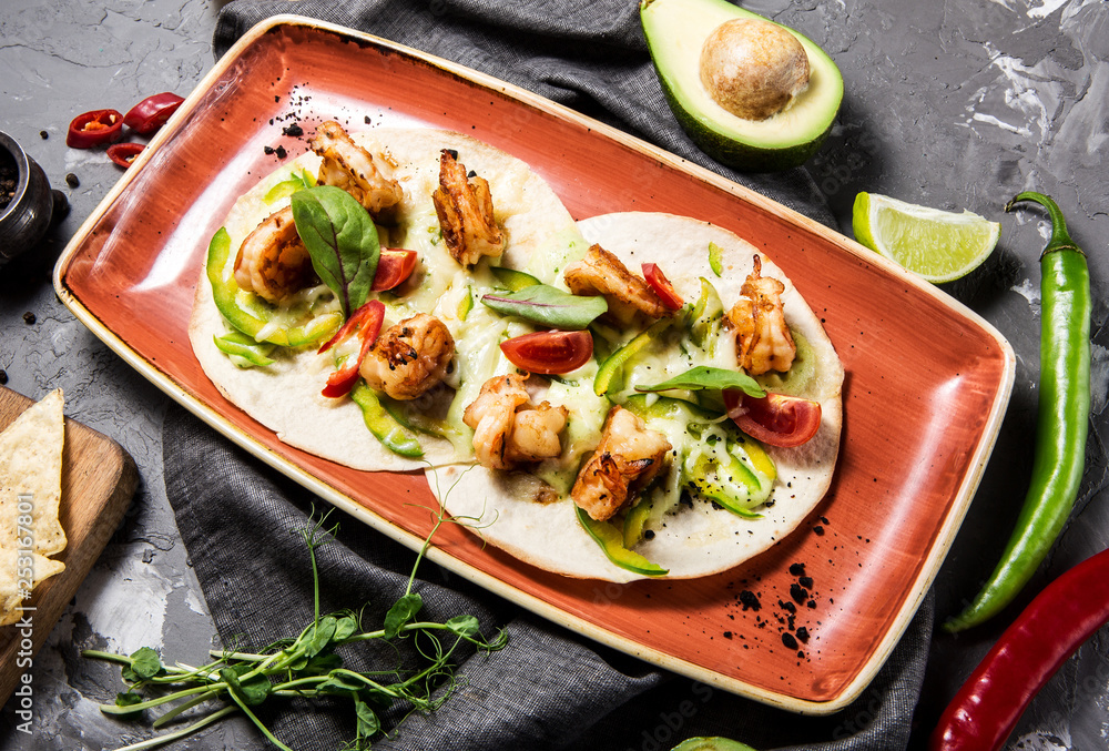 Mexican taco dish with shrimps, bell peppers, tomatoes and chili peppers on a concrete gray background Mexican taco dish with shrimps, bell peppers, tomatoes and chili peppers on a concrete gray background