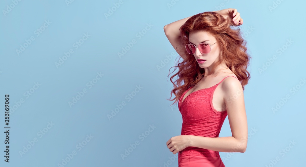 Fashionable shapely Redhead woman with make up wearing Stylish Coral  bodysuit. Beautiful sexy fitness Lady in Trendy lace Attire, fashion  Sunglasses. Slim Female model in Studio Stock Photo