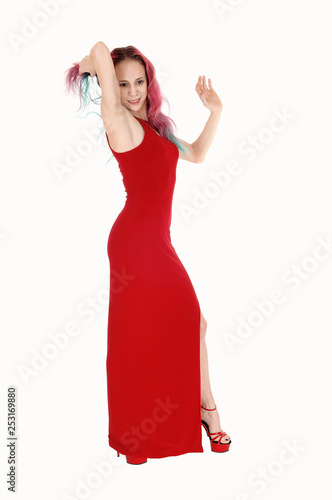 Slim woman standing in a red evening dress in the studio