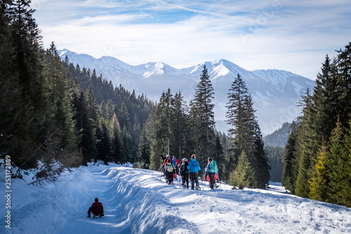 Adults snowshoeing thruogh forest in Kaiserau with mountain Rottenmanner Tauern