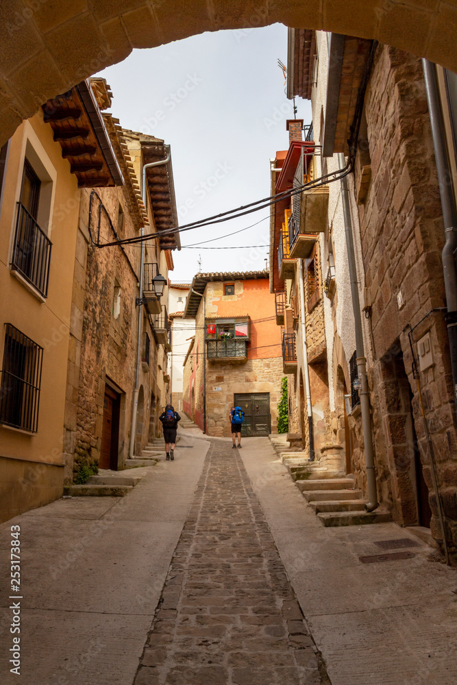 Rear view of pilgrims in a steep street in Cirauqui, Spain on the Way of St. James, Camino de Santiago