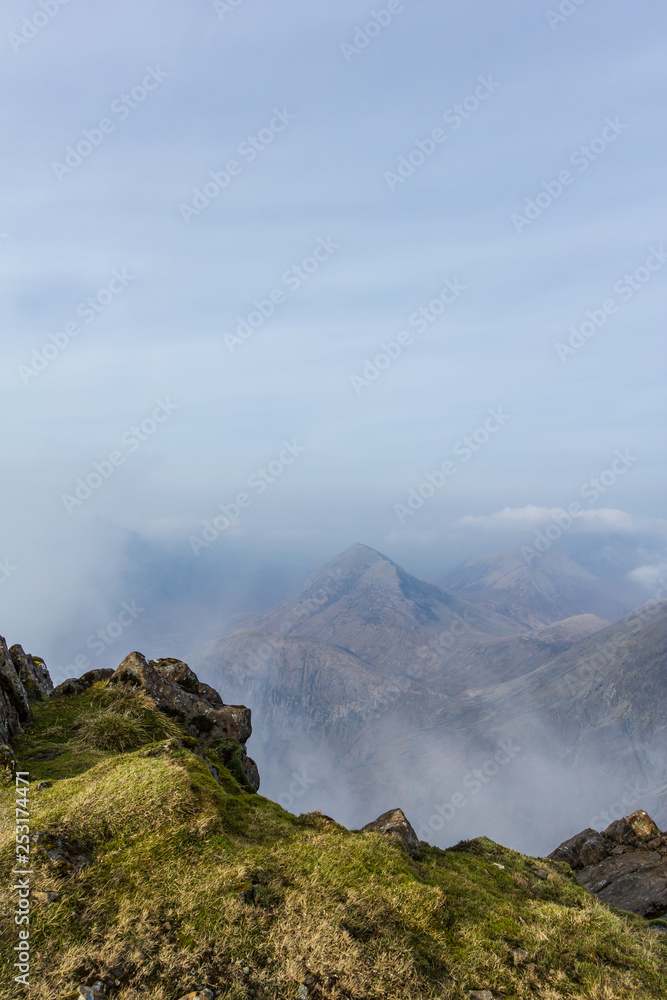 A view from a mountain summit with several other summits and altitude white clouds A view from a mountain summit with several other summits and altitude white clouds
