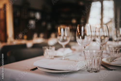 A close up shot of a restaurant table set up with tableware and wine glass. Concept of dining, hospitality and catering. Horizontal image with free space for text.