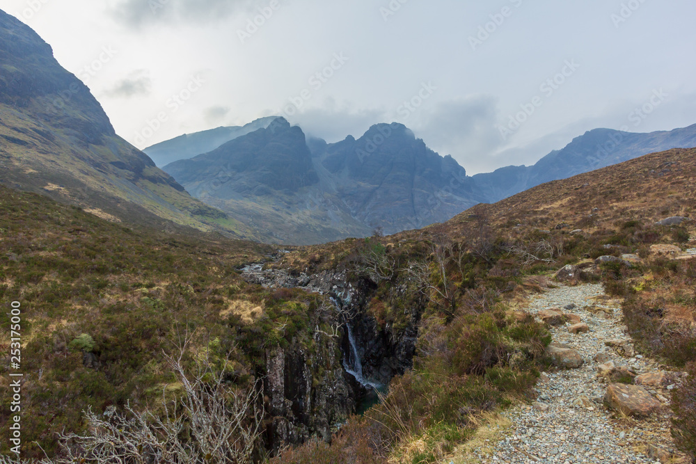 Fototapeta premium On the way to the Bla Bheinn mountain with a water fall and a majestic rocky mountain