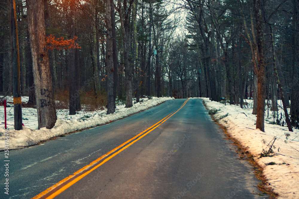Obraz premium Acton, United States, February 27, 2019. Forest road with double yellow line in winter time, Massachusetts, United States