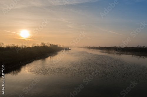 fiume  con argine all alba con nebbia del primo mattino