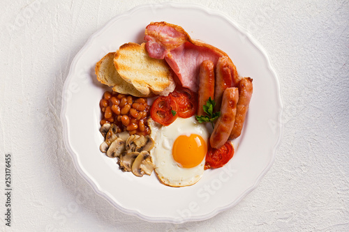 Fotografía Full English or Irish breakfast with sausages, bacon, eggs, tomatoes, mushrooms and beans