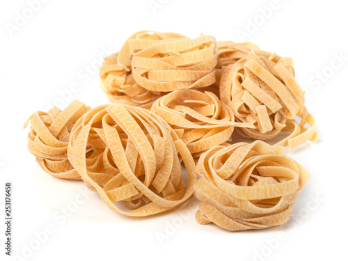 Uncooked nest of tagliatelle Italian pasta isolated on white background