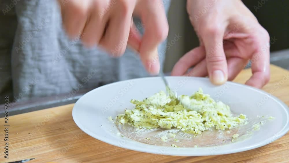 Close-up of female hands with a fork stirred the butter with spices. Home kitchen. For the sauce Close-up of female hands with a fork stirred the butter with spices. Home kitchen. For the sauce