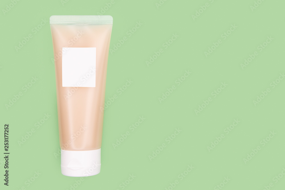 Transparent Plastic Packaging - Tube With White Lid Filled With Beige Cream And Mockup Label On Pale Green Background. Transparent Plastic Packaging - Tube With White Lid Filled With Beige Cream And Mockup Label On Pale Green Background.