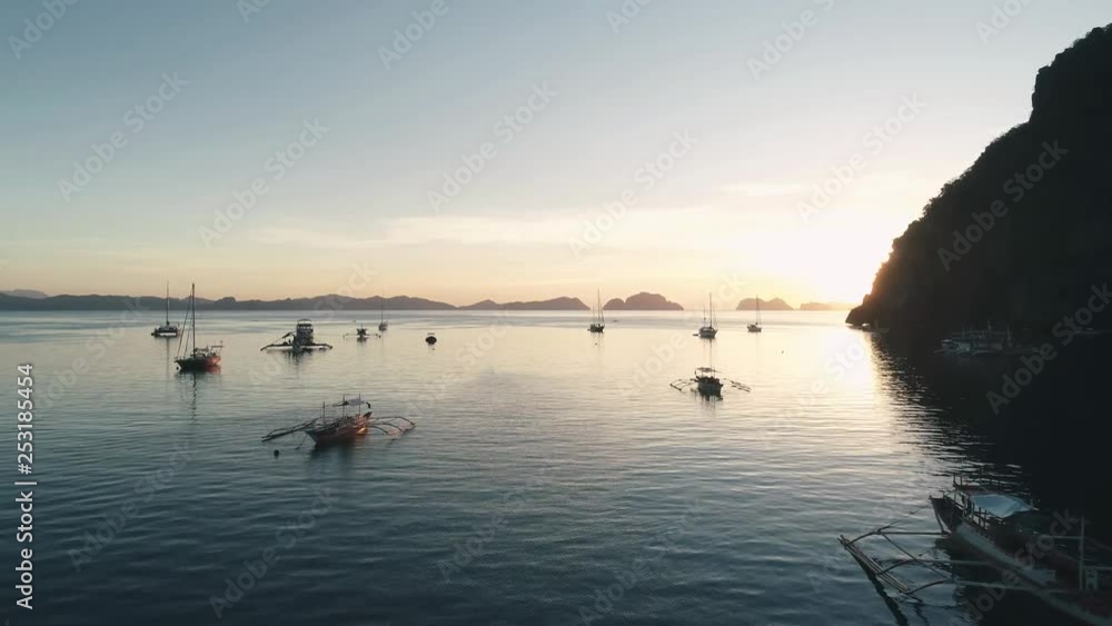 Aerial drone view of boats anchored in the bay with clear and turquoise water on the sunset. Boat and yacht in the tropical lagoon. Tropical landscape. El Nido, Palawan island, Philippines. Aerial drone view of boats anchored in the bay with clear and turquoise water on the sunset. Boat and yacht in the tropical lagoon. Tropical landscape. El Nido, Palawan island, Philippines.