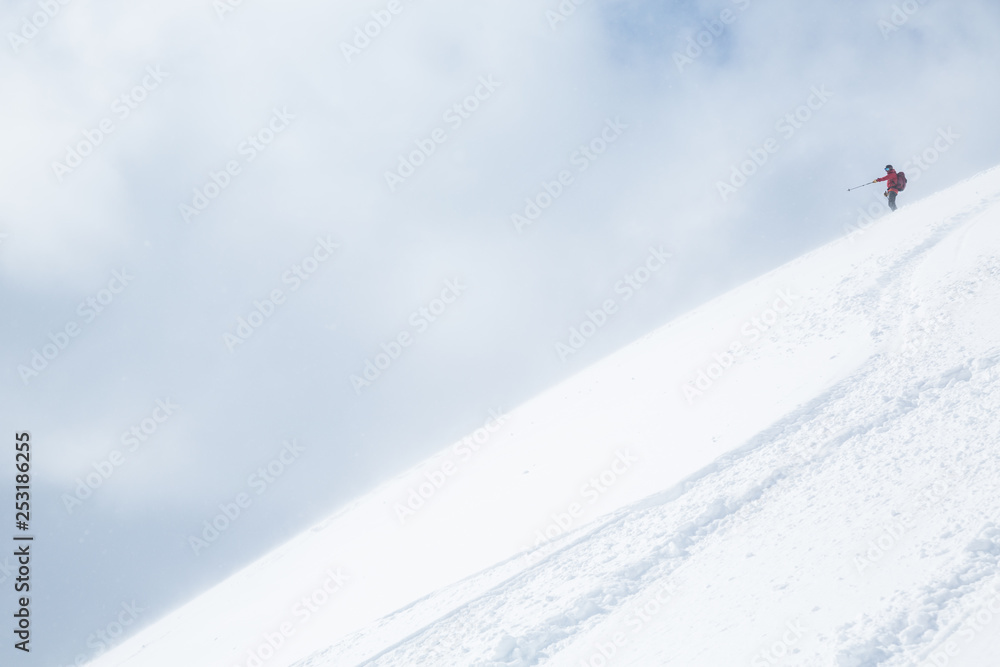 Obraz premium Skier in red pointing down powder covered slope in Japan