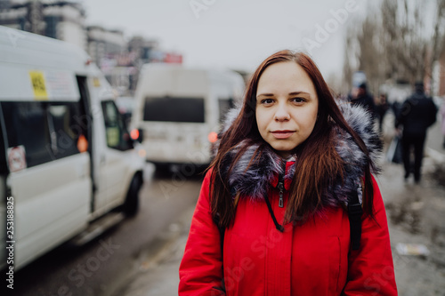 candid street style image of young woman waiting at bus station on a sunny day in winter © Anton Dios