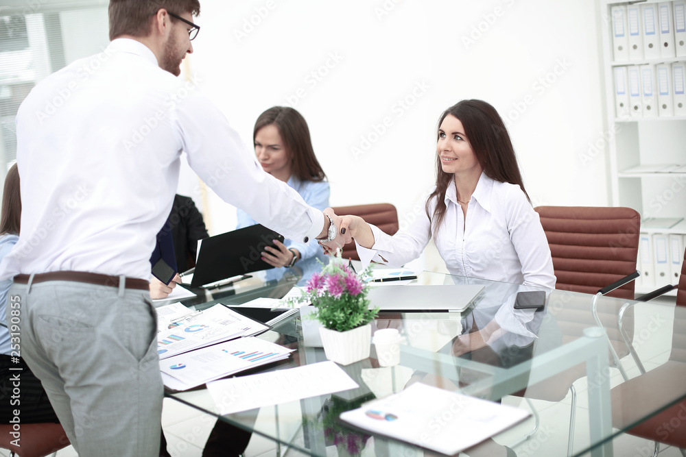 man and woman partners shaking hands over the table, maintaining eye contact