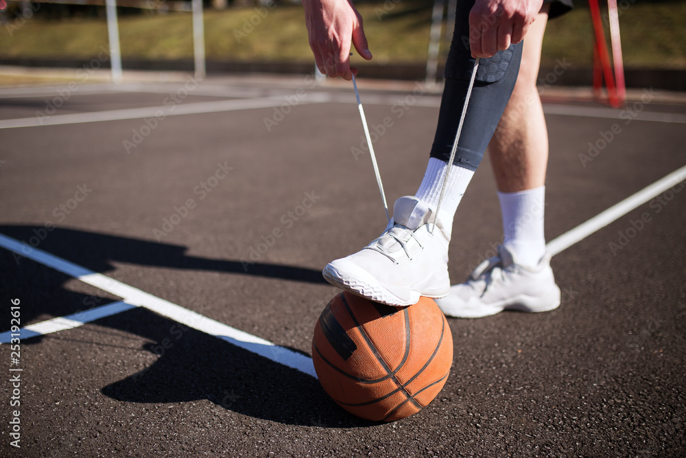 Naklejka premium Basketball player tying shoelace