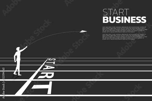 silhouette of businessman throw out origami paper airplane from start line on running track. Business Concept of start business and entrepreneur