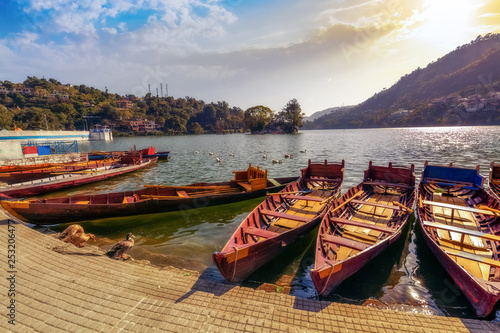 Wooden tourist boats at scenic Bhimtal lake at Nainital Uttarakhand India at sunset with moody sky. photo