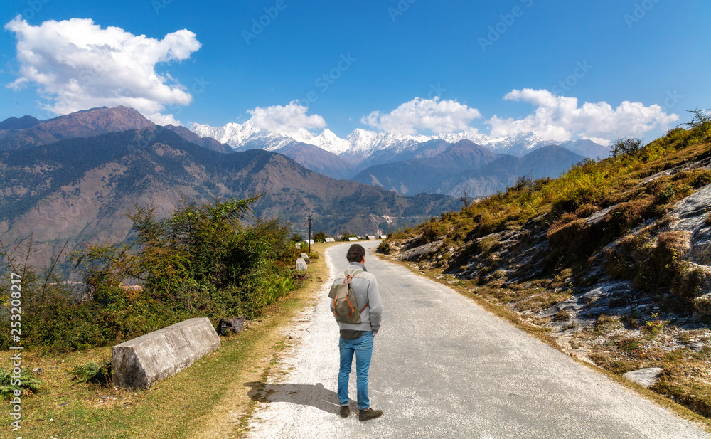 Male tourist backpacker on highway mountain road with view of Himalaya range at Munsiyari Uttarakhand India