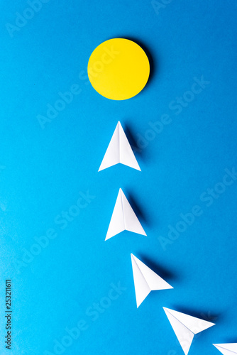 Idea, imagination, solution, light bulb concept. Paper white airplanes with yellow point on blue background.