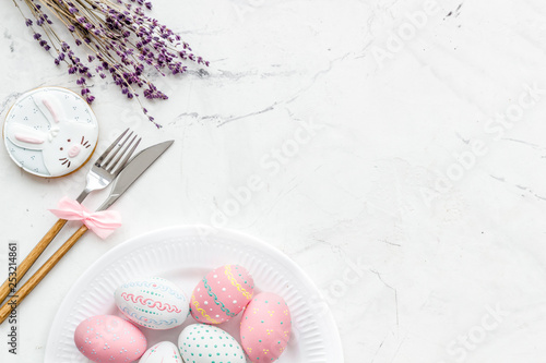 Easter table setting. Tableware and painted eggs on white background top view space for text