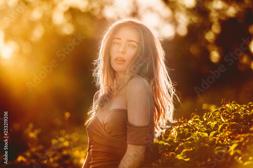 Beautiful woman on green summer glade at sunset time