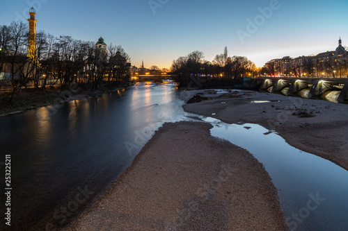 Kiesbänke mit blauem Wasser der Isar mit der Stadt in der Abenddämmerung, München