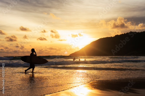 silhouette of man with surfboard on the beach at sunset