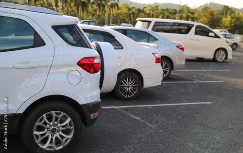 Closeup of back or rear side of white car and other cars parking in outdoor parking area with natural background in twilight evening.  © Amphon