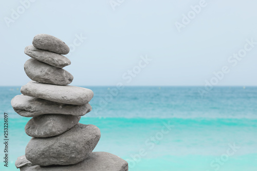 Stack of stones near water. Space for text