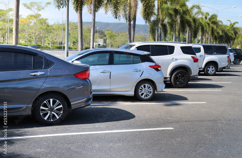 Closeup of back or rear side of blue car and other cars parking in outdoor parking area with natural background in bright sunny day. 