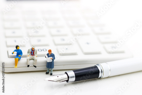 Miniature people: Businessman reading book on calculator, Education or business concept. photo