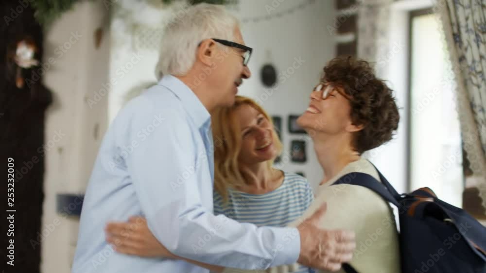 Medium shot of Caucasian woman with short curly hair entering apartment of her relatives and embracing them Medium shot of Caucasian woman with short curly hair entering apartment of her relatives and embracing them