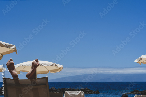 View of the blue sky at a beach on a sunny day with parasols for shade.  © Pranav