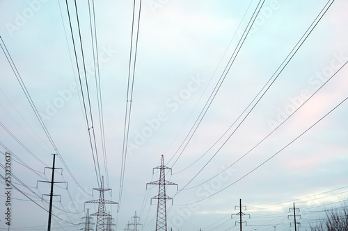 Power lines with many wires and metal supports on the open water against the sky