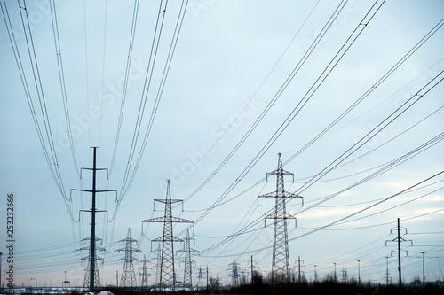 Power lines with many wires and metal supports on the open water against the sky