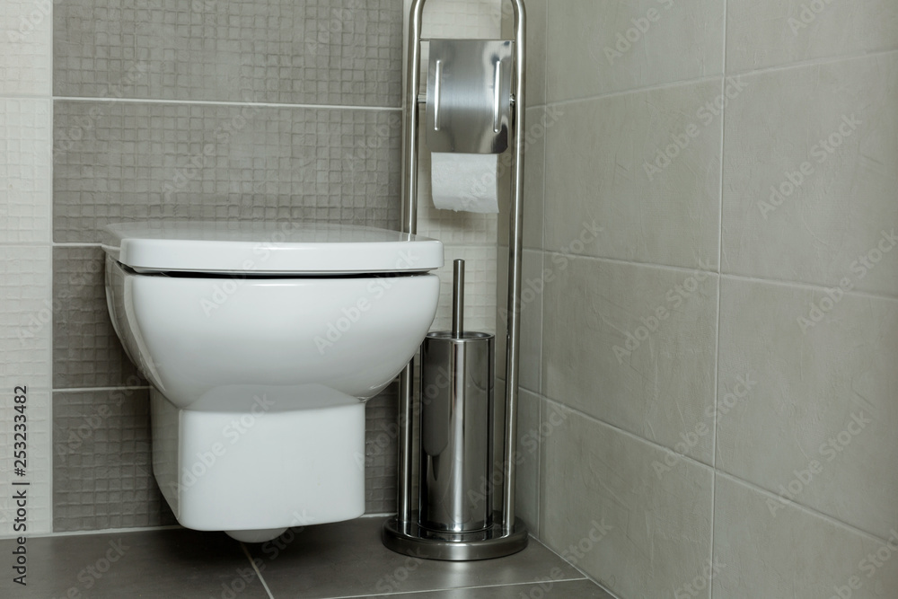 White toilet bowl in modern bathroom with paper holder and toilet brush. White toilet bowl in modern bathroom with paper holder and toilet brush.