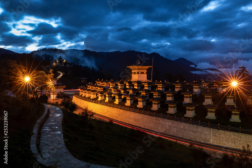 108 chortens of Dochula shining in its glory at dusk with heavy clouds giving company to the blue sky photo